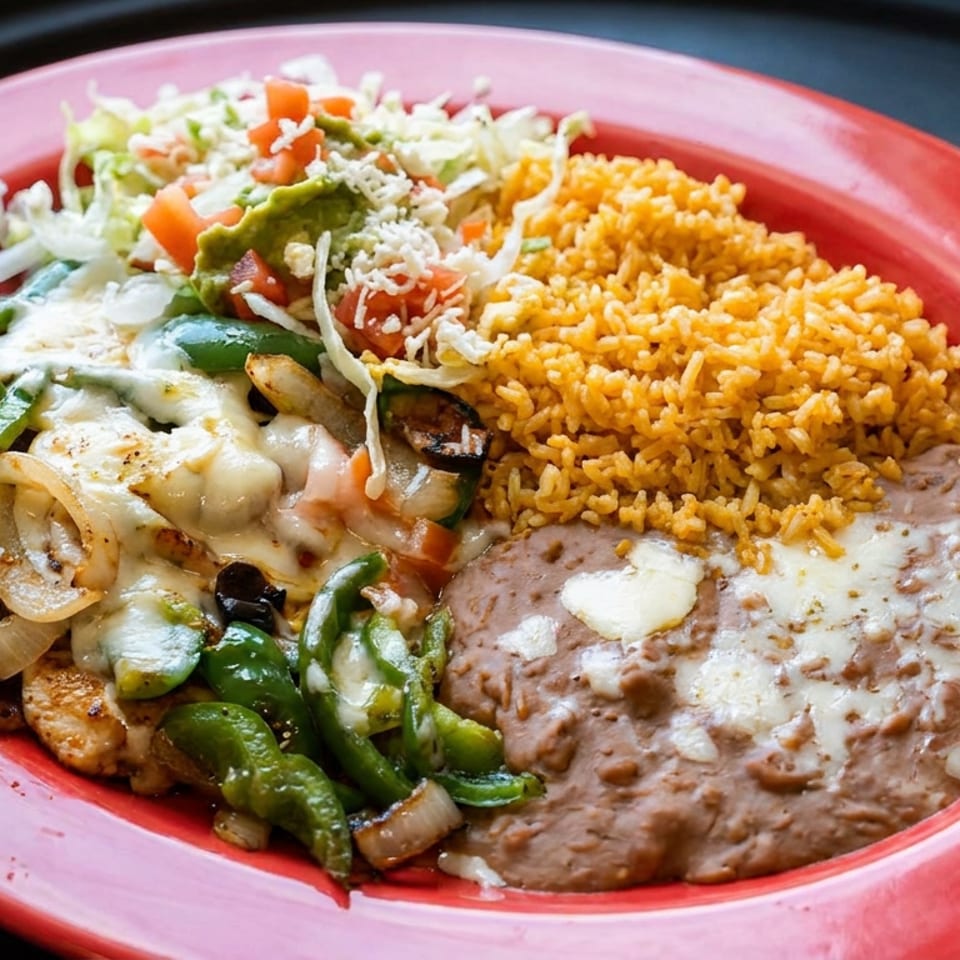 Mexican combination plate with grilled peppers and onions, melted cheese, yellow rice, refried beans, and shredded salad.